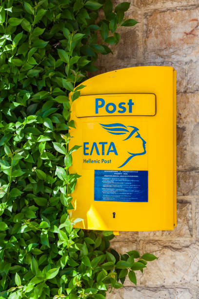 Olympia, Greece - June 30, 2018: A bright yellow Hellenic mailbox on the wall.
